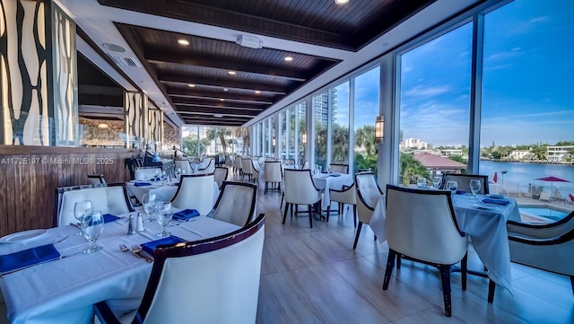 interior space featuring a water view, wood ceiling, light tile patterned floors, and beamed ceiling