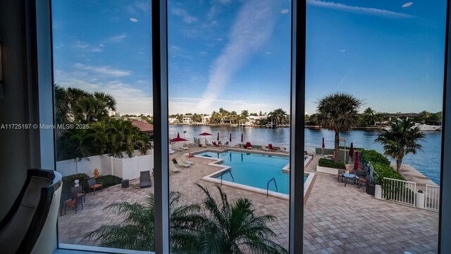 view of swimming pool featuring a water view and a patio