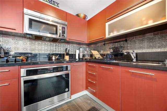 kitchen with stainless steel appliances, hardwood / wood-style flooring, decorative backsplash, and sink