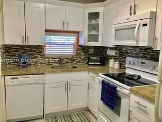 kitchen featuring white cabinets, sink, and white appliances