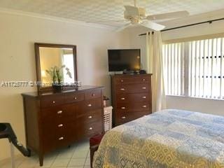 tiled bedroom with ceiling fan and crown molding