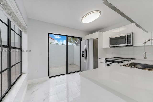 kitchen with white cabinets, decorative backsplash, sink, and stainless steel appliances