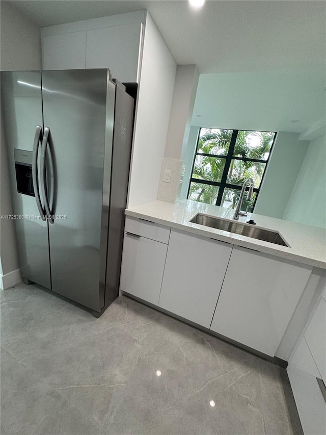 kitchen with white cabinetry, stainless steel fridge with ice dispenser, and sink