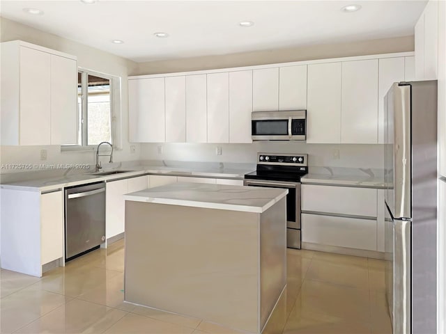 kitchen with appliances with stainless steel finishes, sink, white cabinets, a center island, and light tile patterned floors