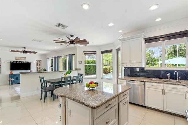 kitchen featuring white cabinetry, stainless steel dishwasher, a kitchen island, and decorative backsplash