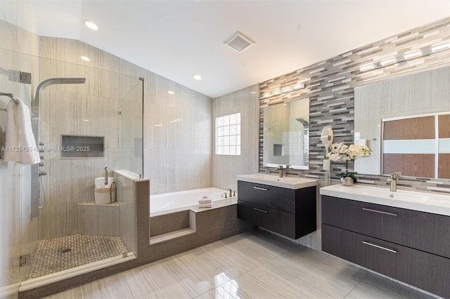 bathroom featuring vaulted ceiling, tile walls, vanity, plus walk in shower, and tile patterned flooring