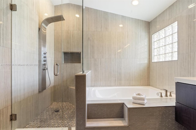 bathroom with plus walk in shower, tile walls, and vanity