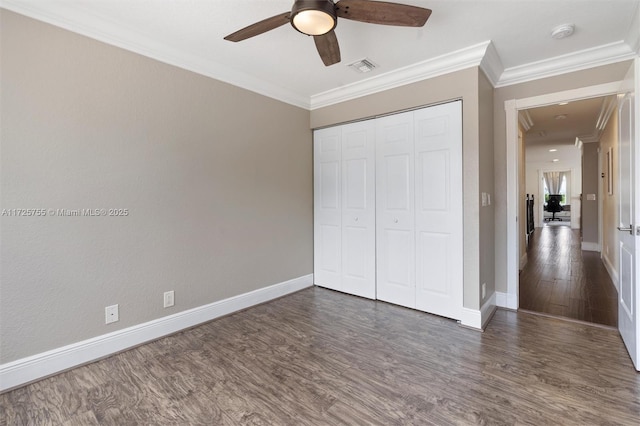 unfurnished bedroom featuring crown molding, dark wood-type flooring, a closet, and ceiling fan