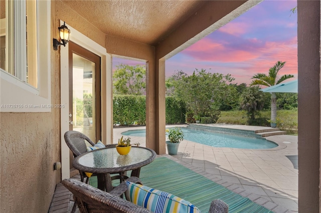 pool at dusk featuring a patio area