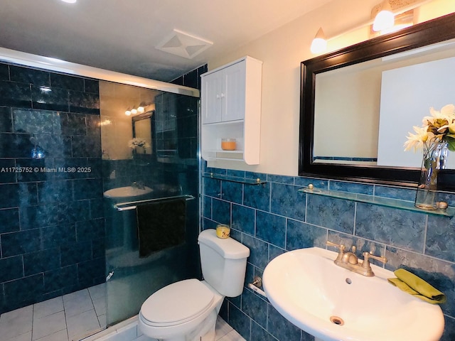 bathroom with toilet, tile patterned floors, tile walls, a shower with door, and sink