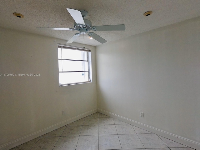 spare room with a textured ceiling, light tile patterned flooring, and ceiling fan