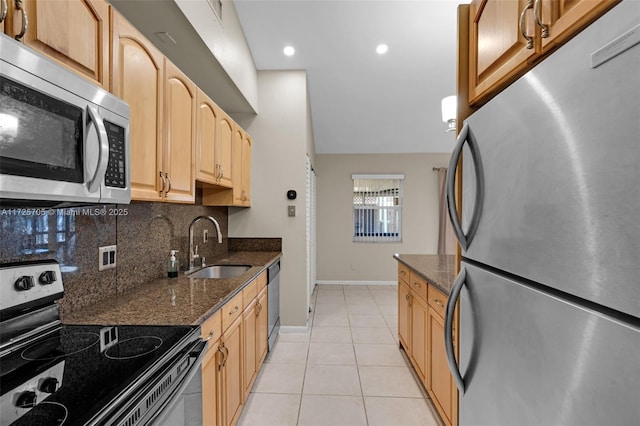 kitchen featuring sink, dark stone countertops, light tile patterned floors, and appliances with stainless steel finishes