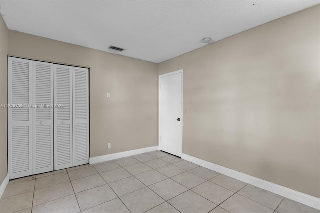 unfurnished bedroom with light tile patterned flooring and a closet