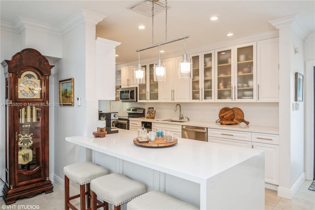 kitchen with pendant lighting, a sink, stainless steel appliances, a breakfast bar area, and light countertops