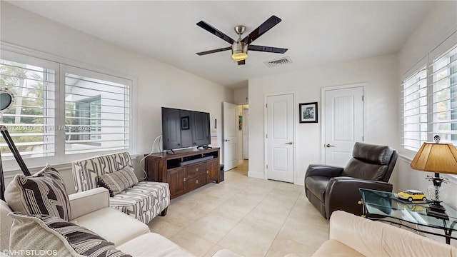 living area with light tile patterned flooring, visible vents, baseboards, and a ceiling fan