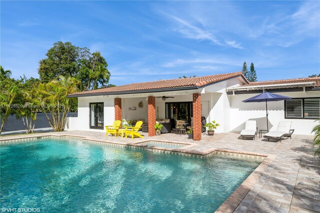 rear view of property featuring fence, a patio area, an outdoor pool, a ceiling fan, and an in ground hot tub