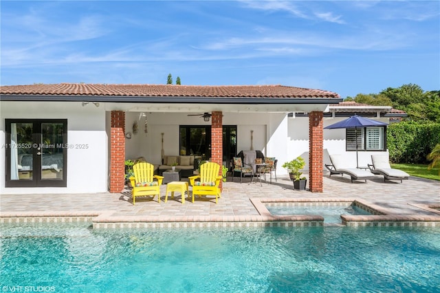 rear view of property featuring stucco siding, a pool with connected hot tub, a patio area, ceiling fan, and a tiled roof