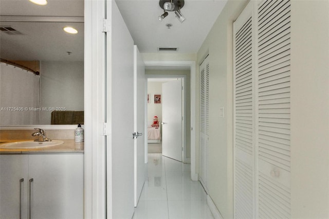 corridor featuring sink and light tile patterned flooring