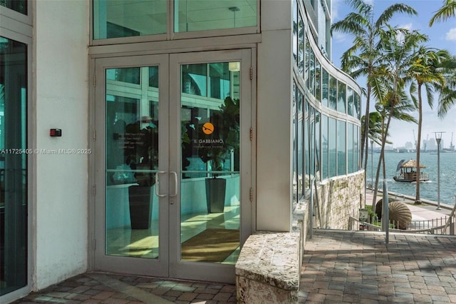 property entrance featuring a patio, french doors, and a water view