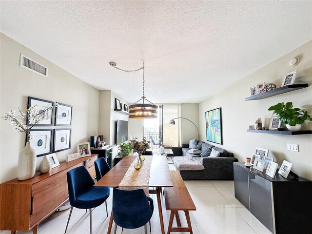 tiled dining area featuring a textured ceiling, an inviting chandelier, and expansive windows