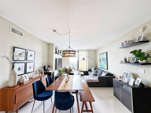 dining area featuring a wall of windows, visible vents, a textured ceiling, and light tile patterned flooring