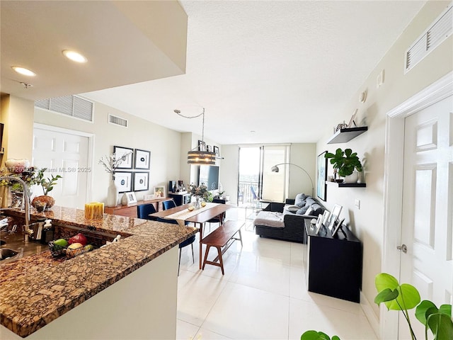 kitchen with dark stone counters, open floor plan, visible vents, and light tile patterned floors