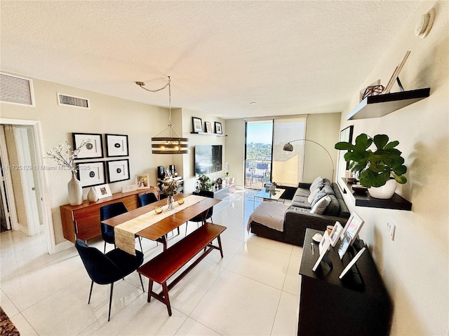 dining space with a textured ceiling, a wall of windows, light tile patterned flooring, and visible vents