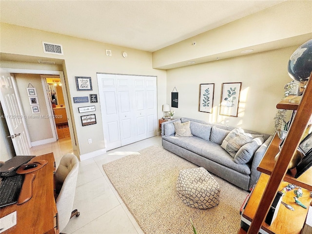 living area featuring light tile patterned flooring, visible vents, and baseboards