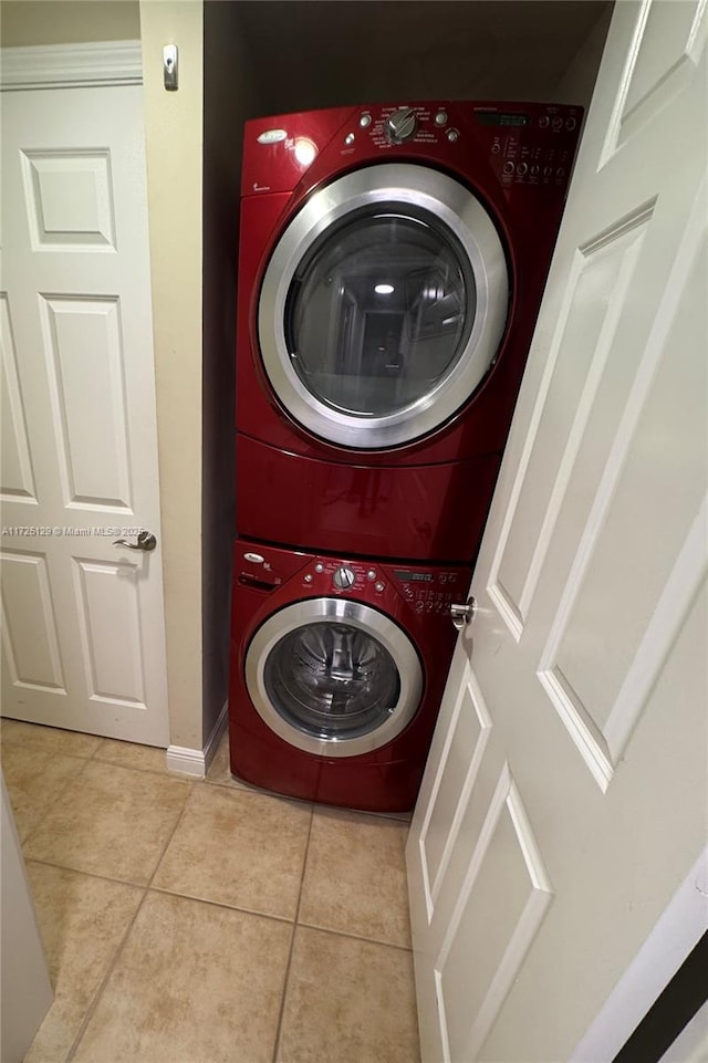 laundry room featuring stacked washer and dryer, baseboards, light tile patterned floors, and laundry area