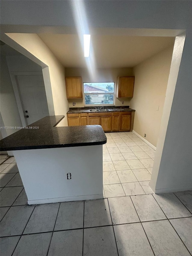 kitchen with kitchen peninsula, light tile patterned floors, and sink