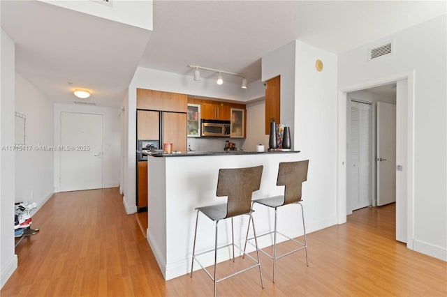 kitchen featuring kitchen peninsula, paneled built in refrigerator, a kitchen breakfast bar, and light hardwood / wood-style flooring