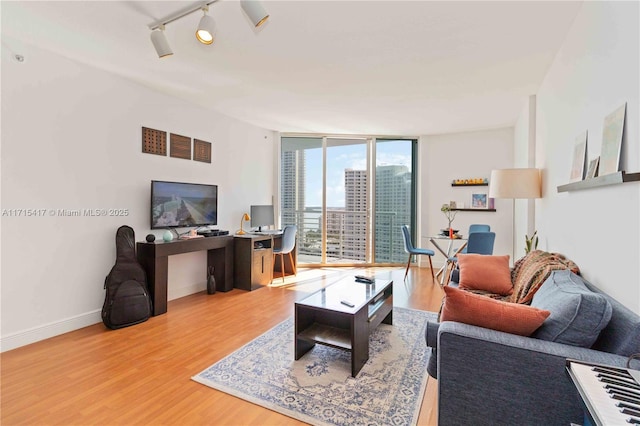 living room featuring rail lighting, expansive windows, and hardwood / wood-style flooring