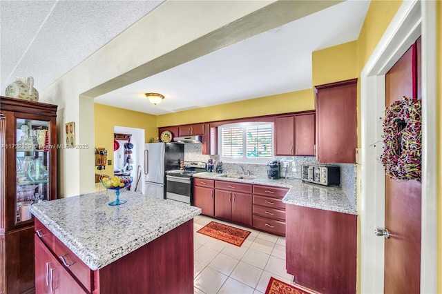 kitchen with appliances with stainless steel finishes, a center island, light tile patterned floors, sink, and tasteful backsplash