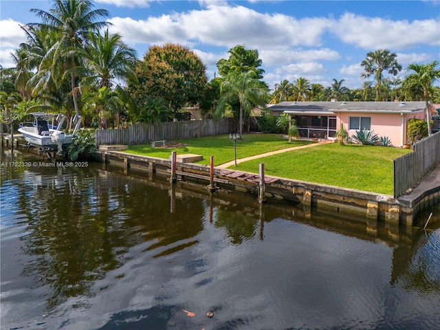 view of dock with a lawn and a water view