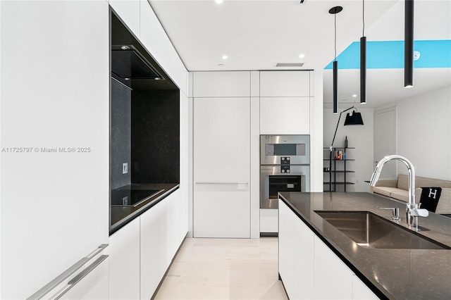 kitchen featuring sink, white cabinetry, black electric cooktop, dark stone counters, and pendant lighting