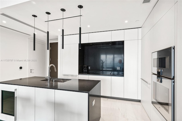 kitchen with sink, white cabinetry, decorative light fixtures, and a kitchen island with sink