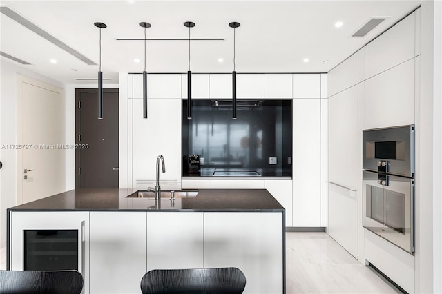 kitchen with beverage cooler, white cabinets, pendant lighting, sink, and oven