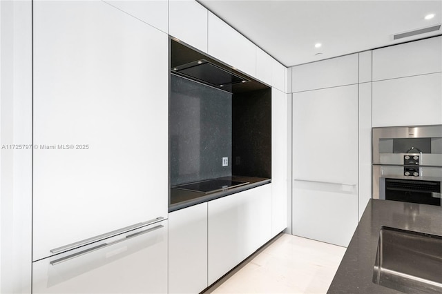 kitchen with white cabinets, stainless steel double oven, backsplash, and black electric cooktop