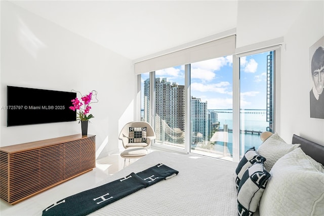 bedroom with a wall of windows, access to exterior, multiple windows, and a water view