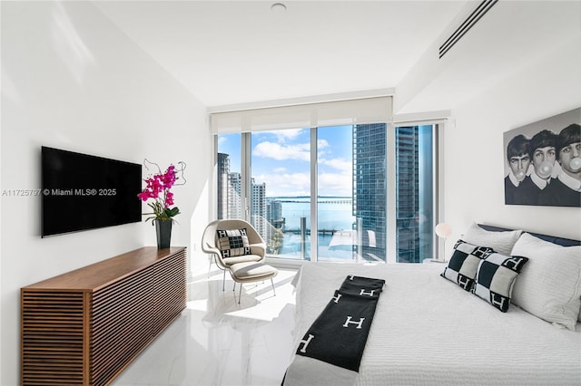 bedroom featuring a wall of windows, multiple windows, and a water view