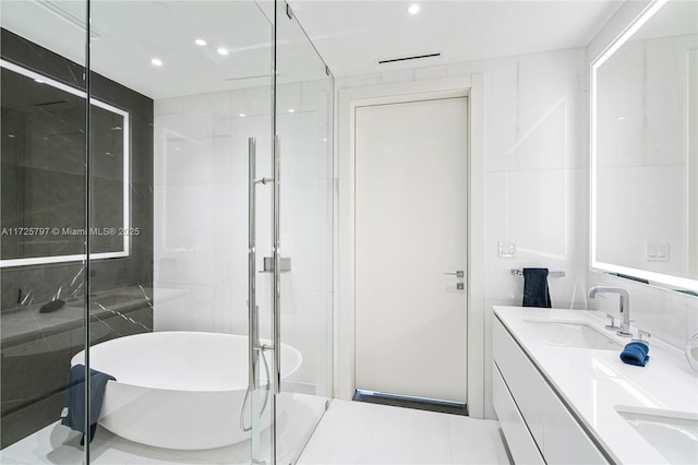 bathroom with tile walls, shower with separate bathtub, and vanity