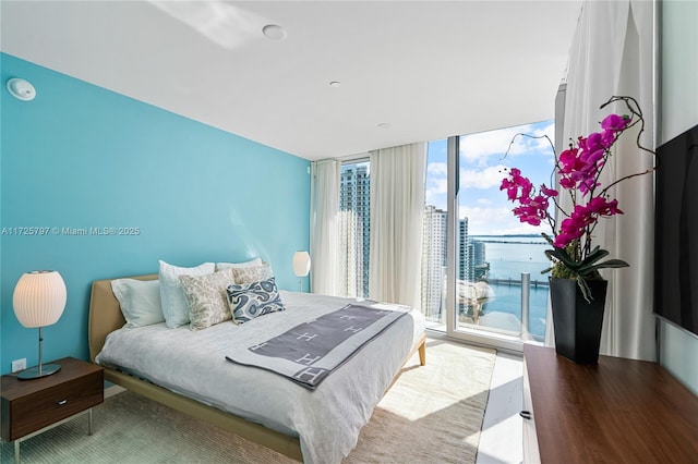 bedroom with wood-type flooring, access to exterior, and expansive windows