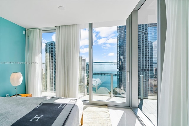 bedroom with access to exterior, a water view, and expansive windows