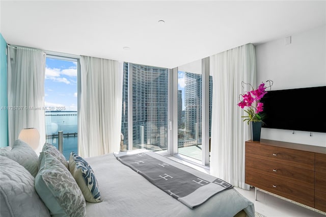 bedroom with a water view, expansive windows, and access to exterior