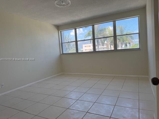 9381 E Bay Harbor Dr Unit 401N, Bay Harbor Islands, FL 33154 - empty room featuring healthy amount of natural light, a textured ceiling, light tile patterned floors, and baseboards