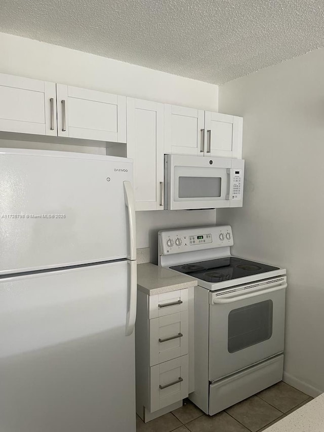 kitchen featuring white appliances, white cabinetry, a textured ceiling, and light tile patterned floors