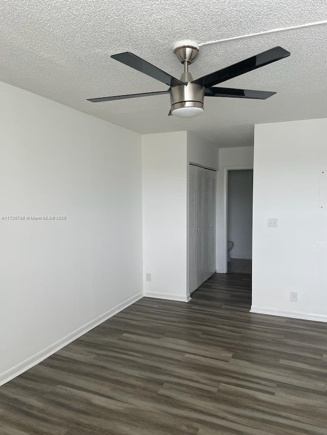 empty room featuring a textured ceiling, ceiling fan, and dark wood-type flooring