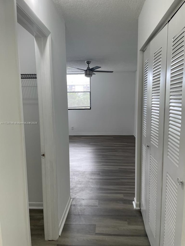 hall with a textured ceiling and dark hardwood / wood-style flooring