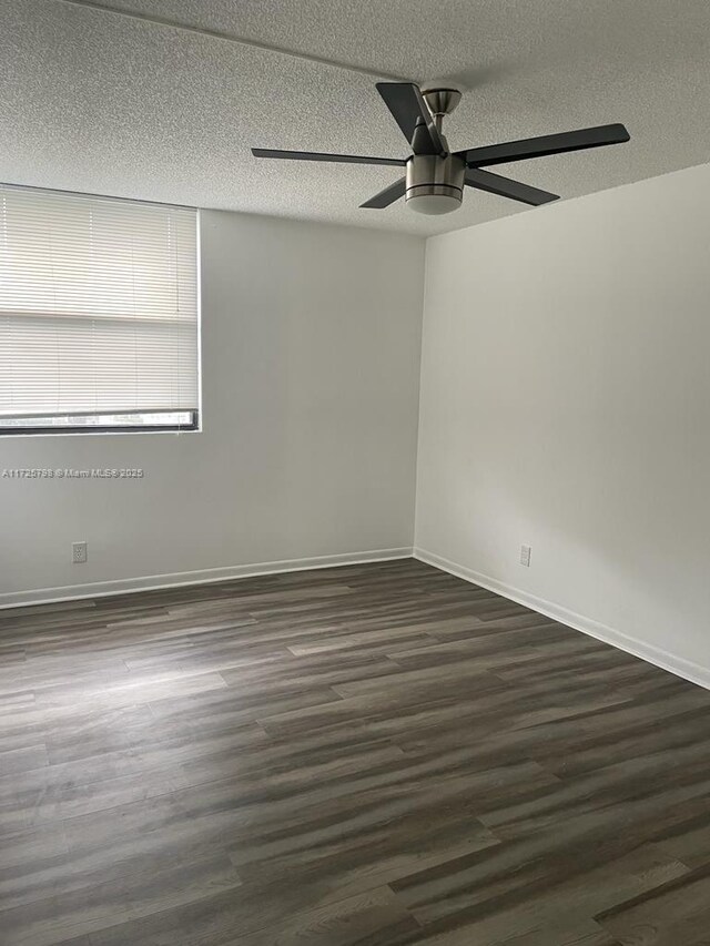 empty room featuring a textured ceiling, ceiling fan, and dark wood-type flooring