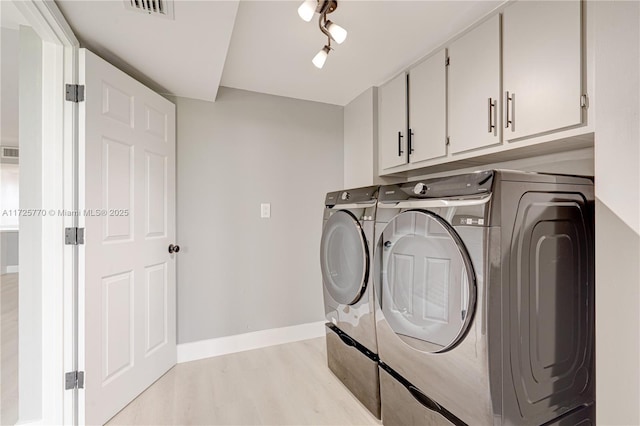 laundry room with track lighting, light wood-type flooring, cabinets, and independent washer and dryer